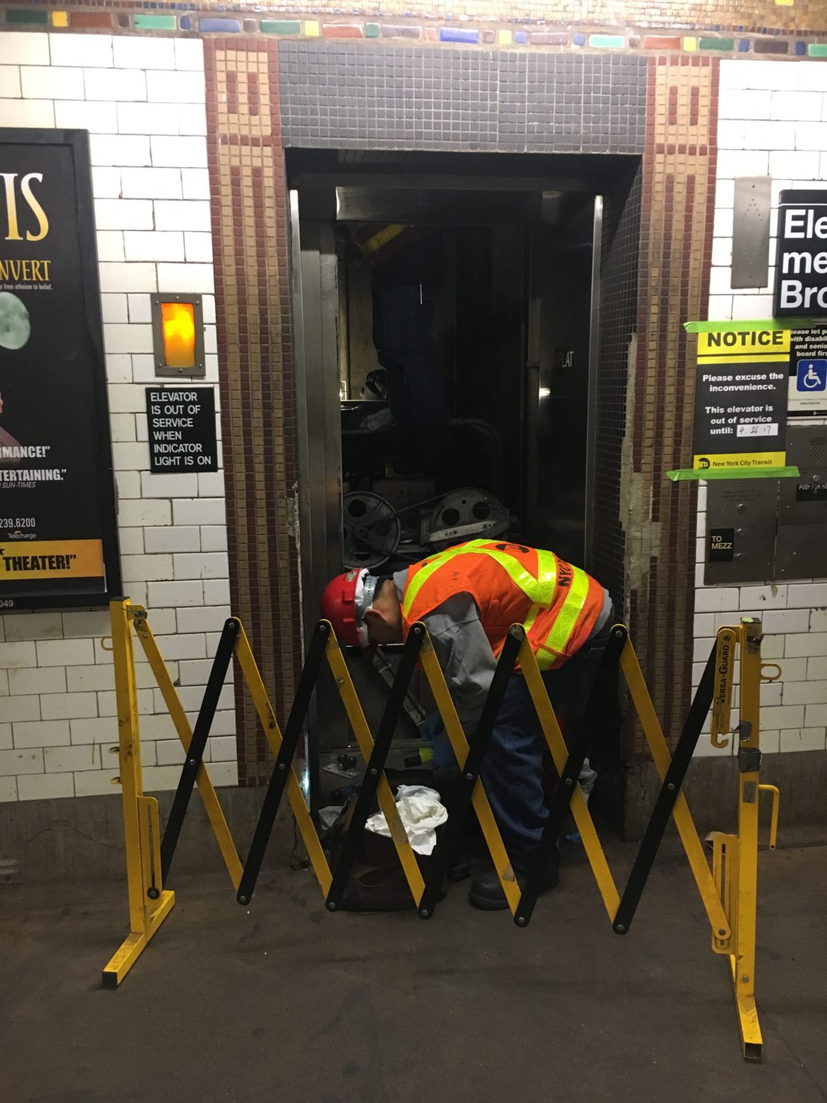 Person i safety-vest repairing an elevator behind a Portable Barricade