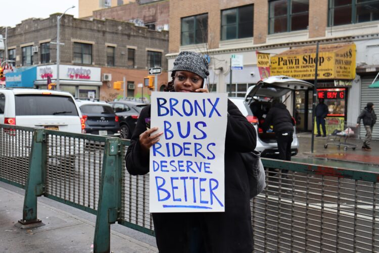 A rider holds a sign saying, "Bronx Bus Riders Deserve Better."